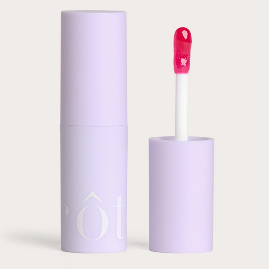 Côte Beauty The Necessity Peptide Lip Shine Lola Magenta Pink Non-Toxic Lip Gloss in a tube with an open cap beside. 