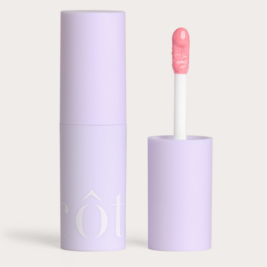 Côte Beauty The Necessity Peptide Lip Shine Lyla Light Pink Non-Toxic Lip Gloss in a tube with an open cap beside. 
