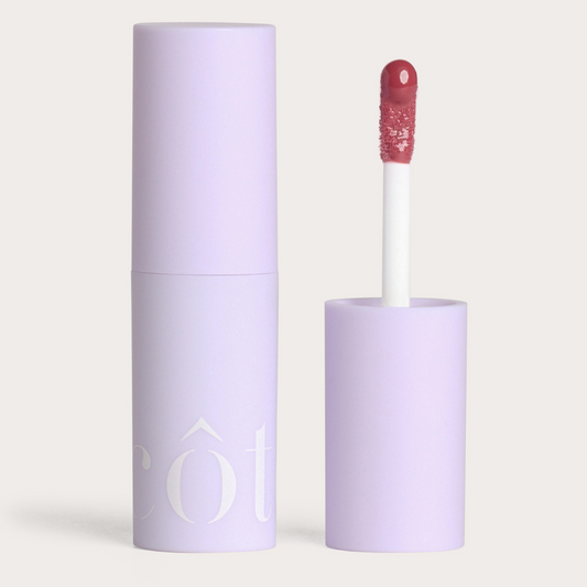 Côte Beauty The Necessity Peptide Lip Shine Mulberry Milky Mauve Non-Toxic Lip Gloss in a tube with an open cap beside it. 