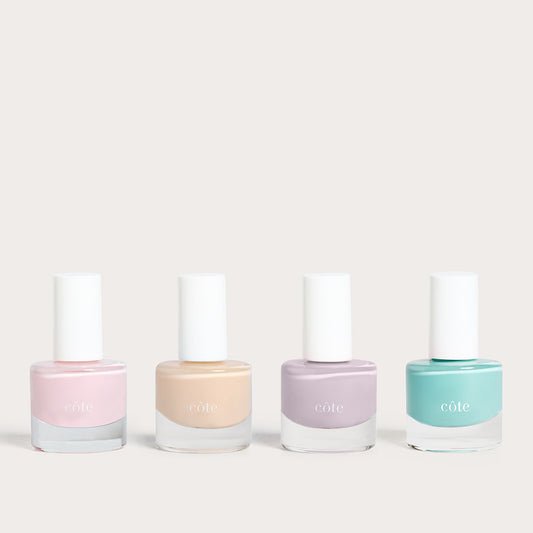 Côte Beauty Summer Vows Set, four nail polish bottles in blush pink, nude beige, soft violet grey and fresh aqua blue on a neutral background.